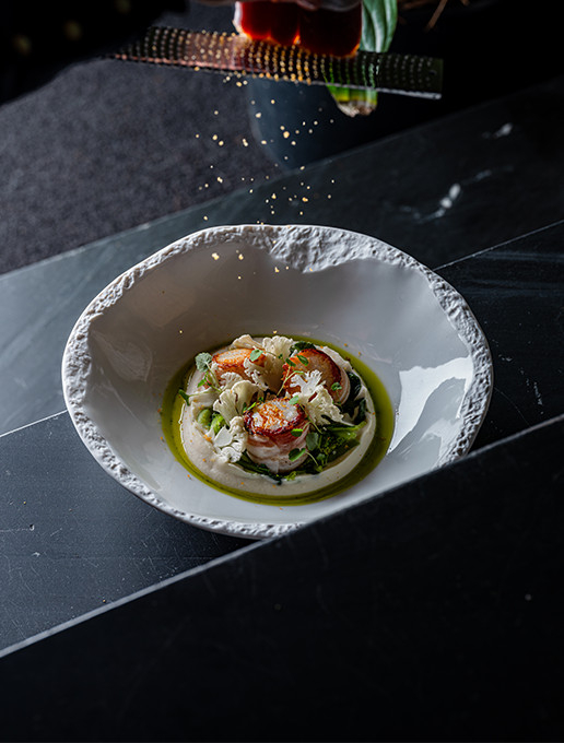 Plat raffiné de Saint-Jacques dressé avec une émulsion et légumes croquants, servi au restaurant Dans le Noir ?