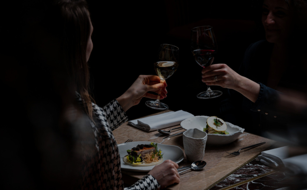 Deux convives trinquent dans un restaurant Dans le Noir ?, partageant un repas sensoriel inédit dans l’obscurité totale à Tours.